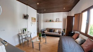 Un espacio habitable moderno con comedor, sofá y un portátil sobre una mesa de cristal.