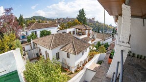 Zona residencial con tejados de teja anaranjada, paredes blancas y vistas a una colina distante.