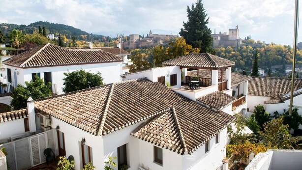 Zona residencial con edificios blancos, tejados de teja y vistas a colinas distantes.