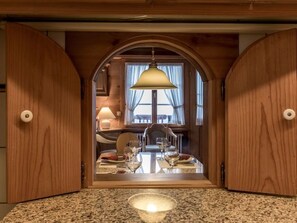 Ein Essbereich mit einem Tisch für zwei Personen, einer Chandelier und Blick durch einen Bogen.
