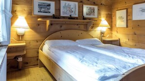 Una stanza in legno con un letto, due lampade a parete e tre quadri appesi.