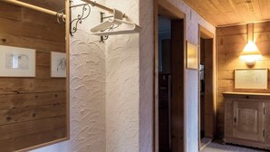 Un corridoio con pareti in legno, un lampadario a sospensione e una porta che conduce in un'altra stanza.
