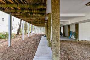 An outdoor covered area with wooden pillars, a gravel path, and a building in the background. - Charming Oceanside Getaway! (Bethany Beach)