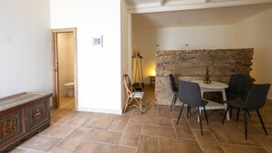 Ein Zimmer mit Steinsandsteinwand, einer Holzbk, einem Esstisch mit Stühlen und einem Schaukelstuhl.