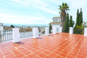 A terrace with red tiles, white pillars, and a view of the cityscape. - The Cascajal Oven (Granada)