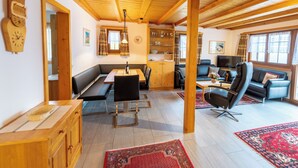Una habitación amplia con vigas de madera, zona de comedor, sofá y televisor.