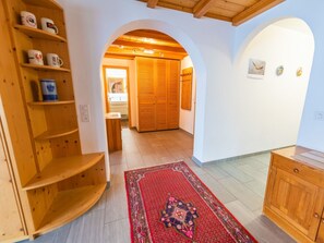 Un pasillo con estanterías de madera, un tapete de diseño rojo y un armario de madera.