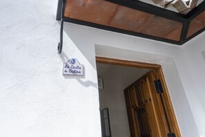 Eine weiße Wand mit einem Schild, auf dem 'La Casa de Cristina' steht, und einem hölzernen Türrahmen.