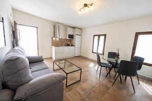 Ein modernes Wohnzimmer mit einer Couch, einem Glastisch und einem Essbereich mit Stühlen und einem Tisch.