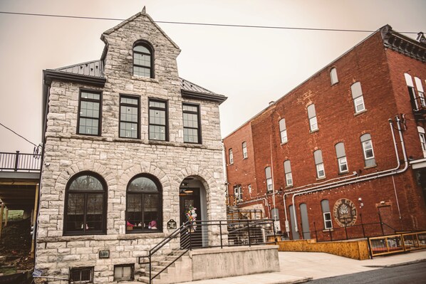 A stone building with a central entrance, a staircase, and a brick building adjacent to it.