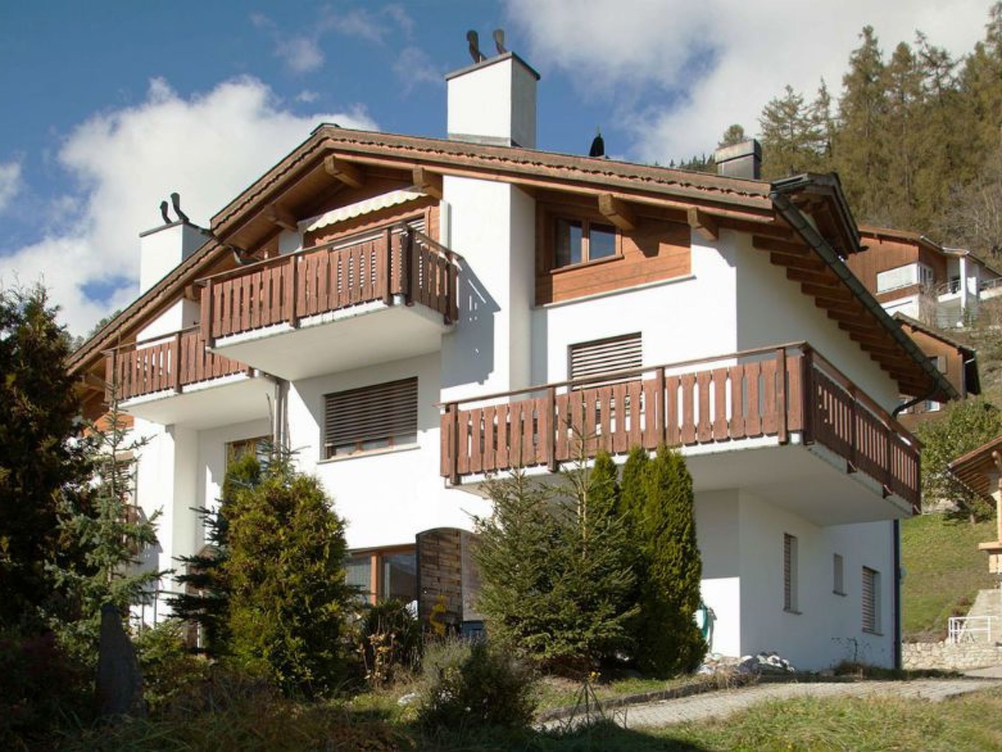 Ein mehrstöckiges Gebäude mit Balkonen, einem Schornstein und einer weißen Fassade.