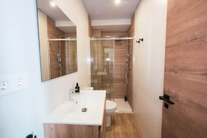 Ein modernes Badezimmer mit einem weißen Waschbecken, einer Toilette und einer Duschkabine.