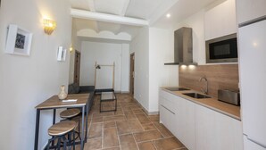A modern kitchen with a dining area, a microwave, a sink, and a hanging rack. - San Miguel Bajo Apartment (Granada)