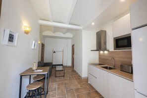 A modern kitchen with a dining area, a microwave, a sink, and a hanging rack. - San Miguel Bajo Apartment (Granada)