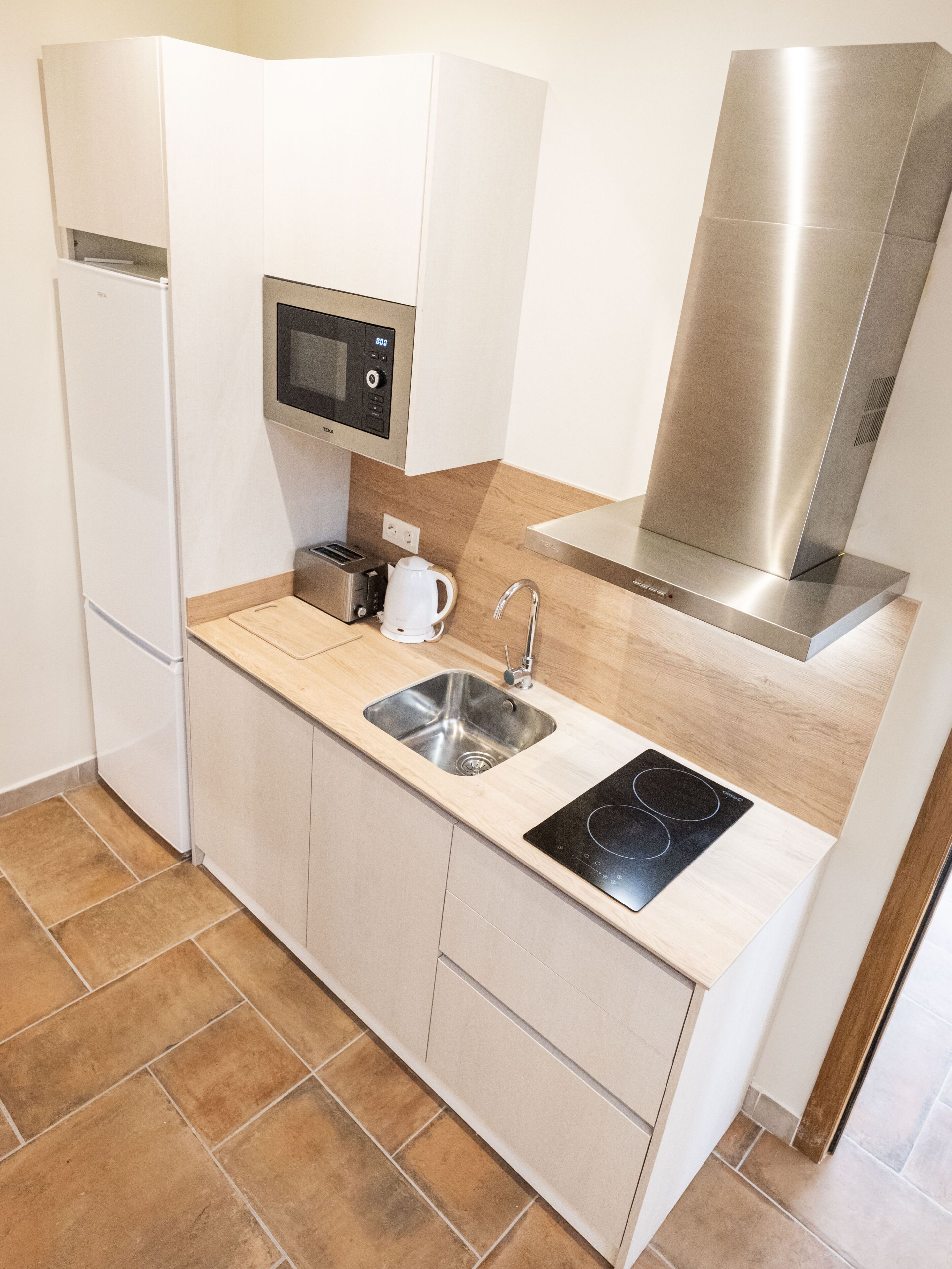 A compact kitchen with a built-in microwave, toaster, sink, and stove.