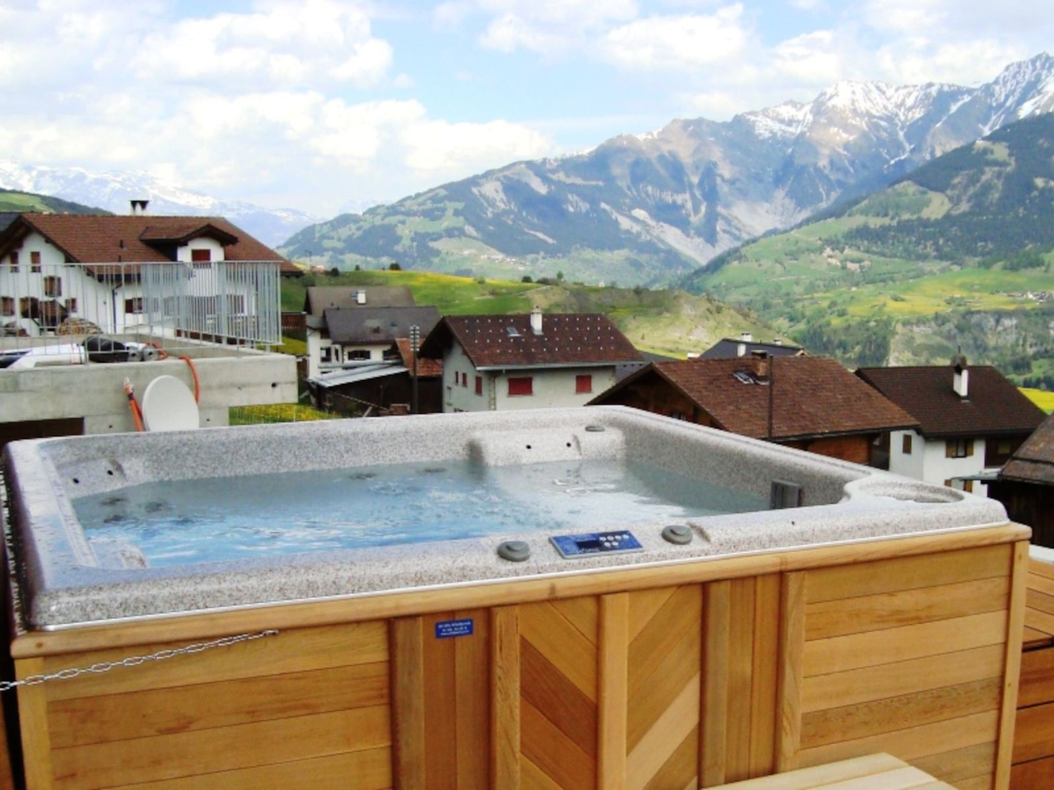 A hot tub on a deck with a mountainous backdrop.