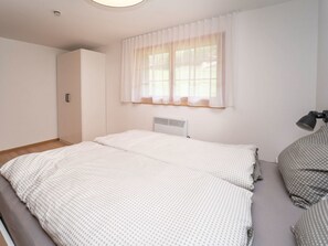 Ein Schlafzimmer mit einem Bett, einem Kleiderschrank, einem Fenster mit Vorhängen und einer Heizung.