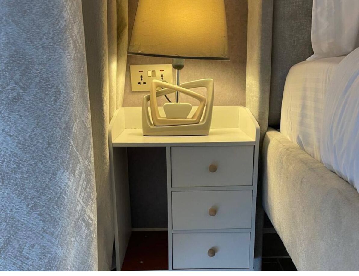 A small bedside table with a lamp, a power outlet, and a drawer.