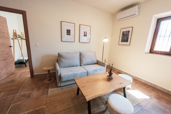 Een woonkamer met een bank, een houten tafel, een vloerlamp en een raam.