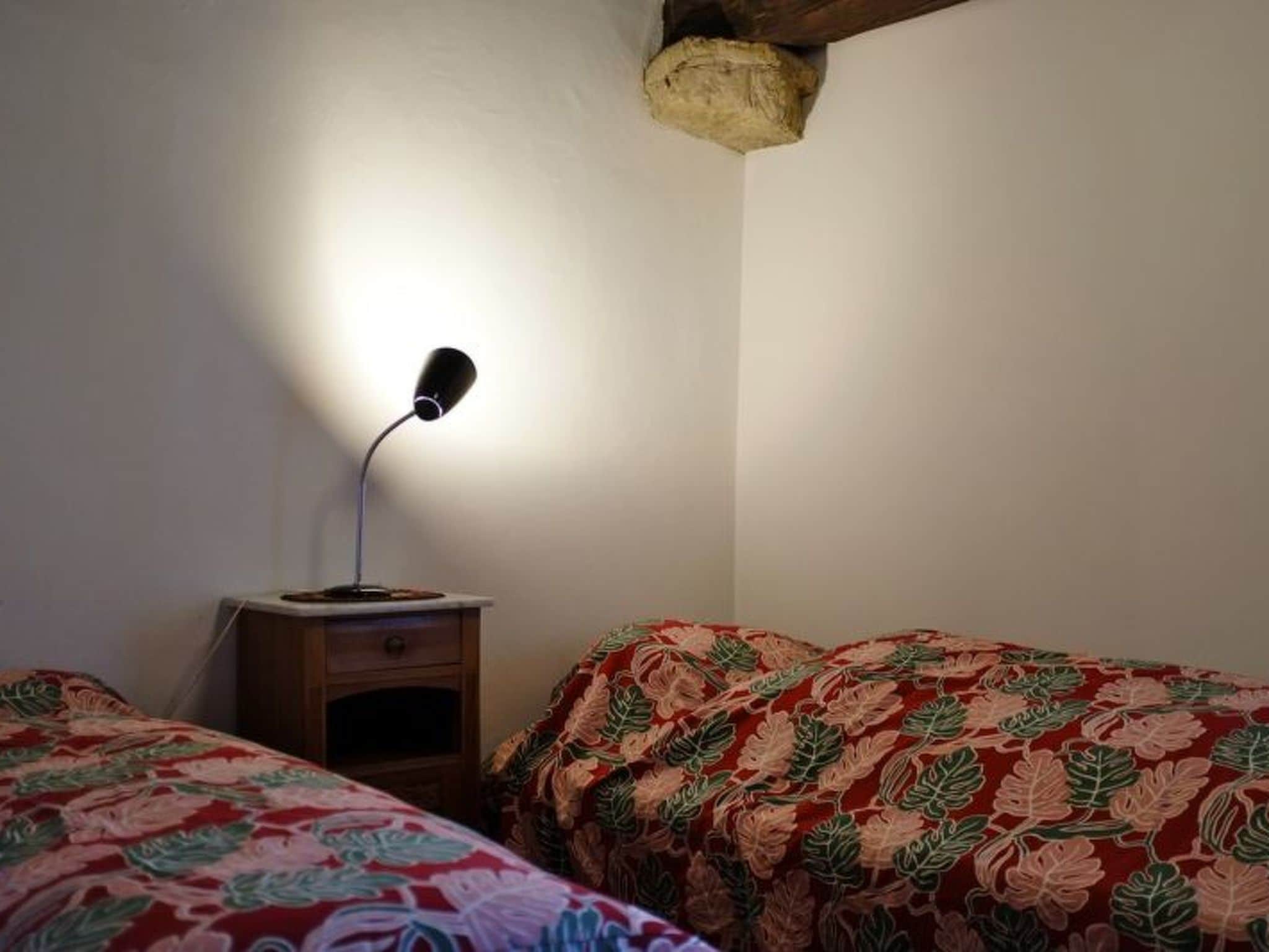 Une chambre avec deux lits, une table de chevet et une lampe.