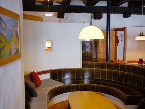 A curved seating area with a bench and a table, a hanging light fixture, and a small wall-mounted light.