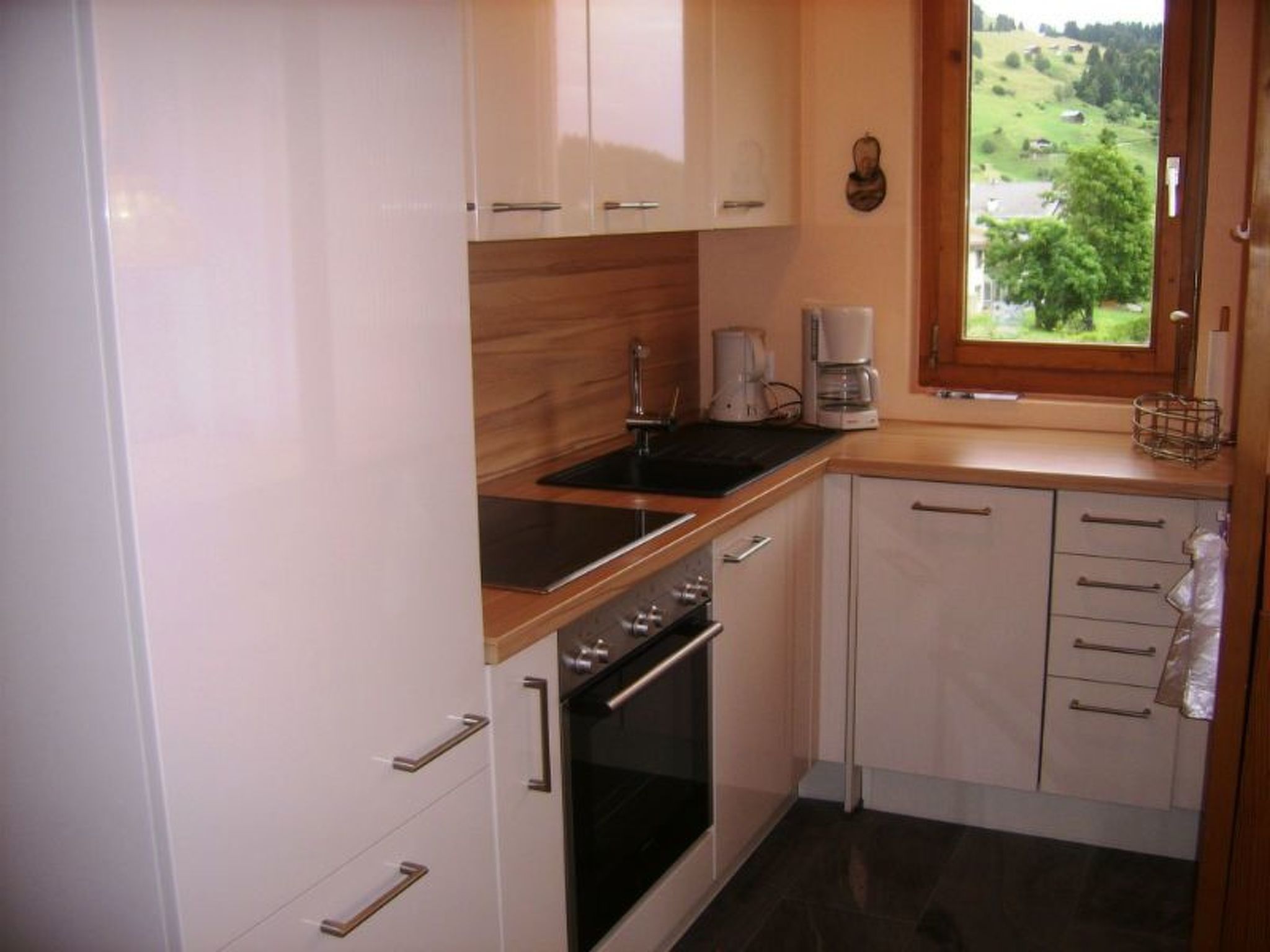 A compact kitchen with a sink, stove, and coffee maker.
