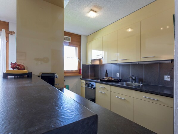 A modern kitchen with light-colored cabinets, a dark countertop, and a window providing natural light.