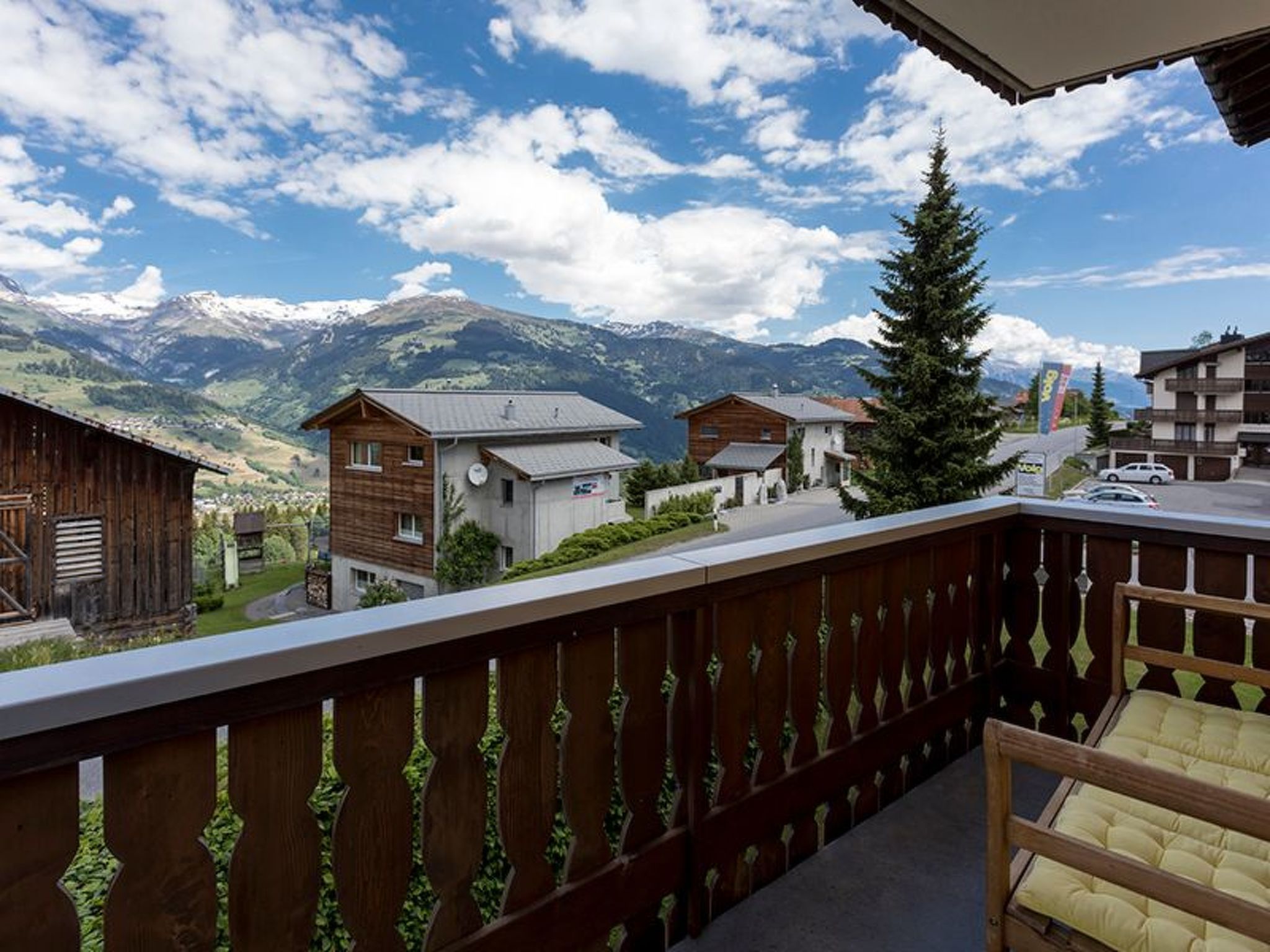 Un balcon donnant sur une chaîne de montagnes et agrémenté d’une clôture en bois.