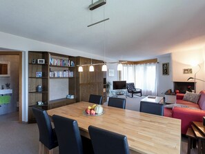 Un espacio moderno de estar con comedor, una zona de descanso acogedora y una estantería.