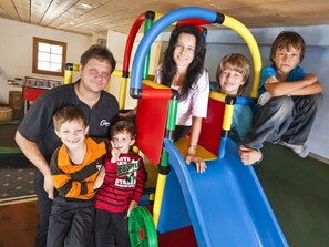 A family of five at a playground with a slide. - Alpina Schmed, Brigels, (Breil/Brigels), 65002B by Interhome (Breil/Brigels)