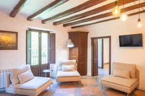 Une pièce comprenant un canapé, un fauteuil, une table, un téléviseur et un tableau accroché au mur.