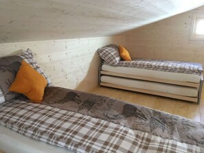 Una habitación con una cama elevada y un sofá cama, ambos con ropa de cama a cuadros.
