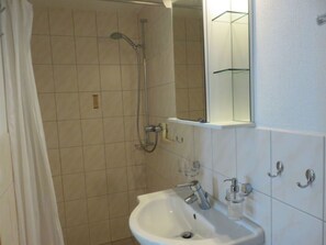 A bathroom with a shower, a sink, and a mirror.