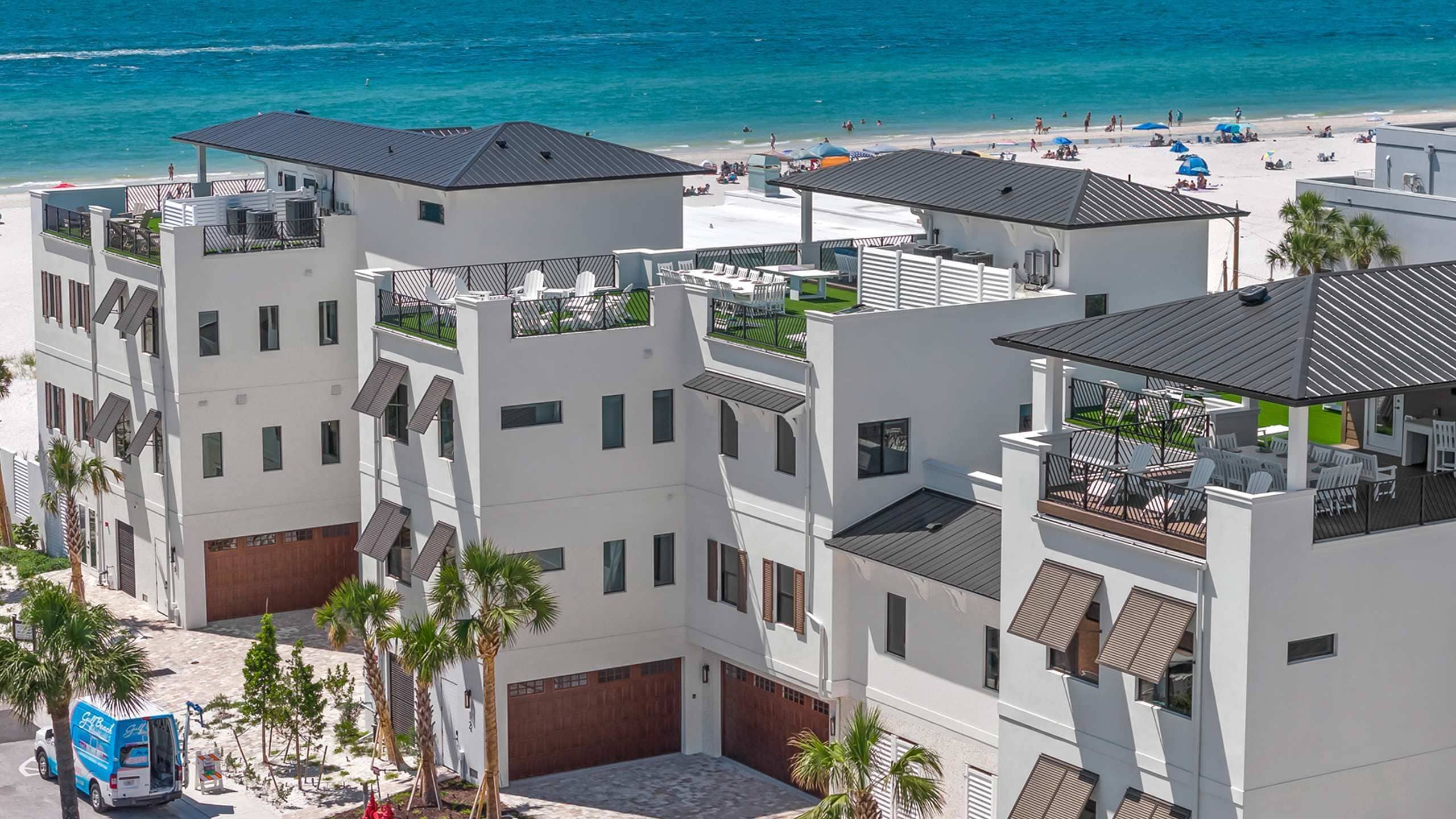 A modern hotel with multiple balconies, a beach view, and a pool area.