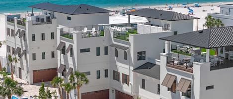 A modern hotel with multiple balconies, a beach view, and a pool area.