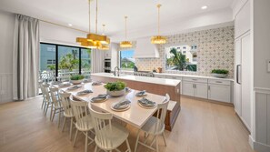 A modern kitchen with a central island, white cabinetry, and pendant lighting. - Pool, Spa & Rooftop Retreat - Direct Beach Access (Clearwater)