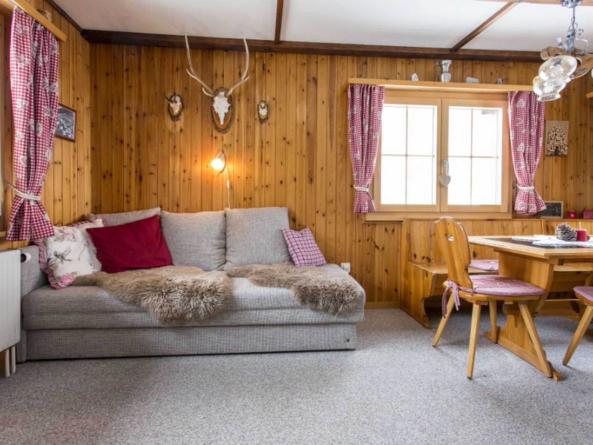 A cozy cabin interior with a sofa, a dining table, and chairs.
