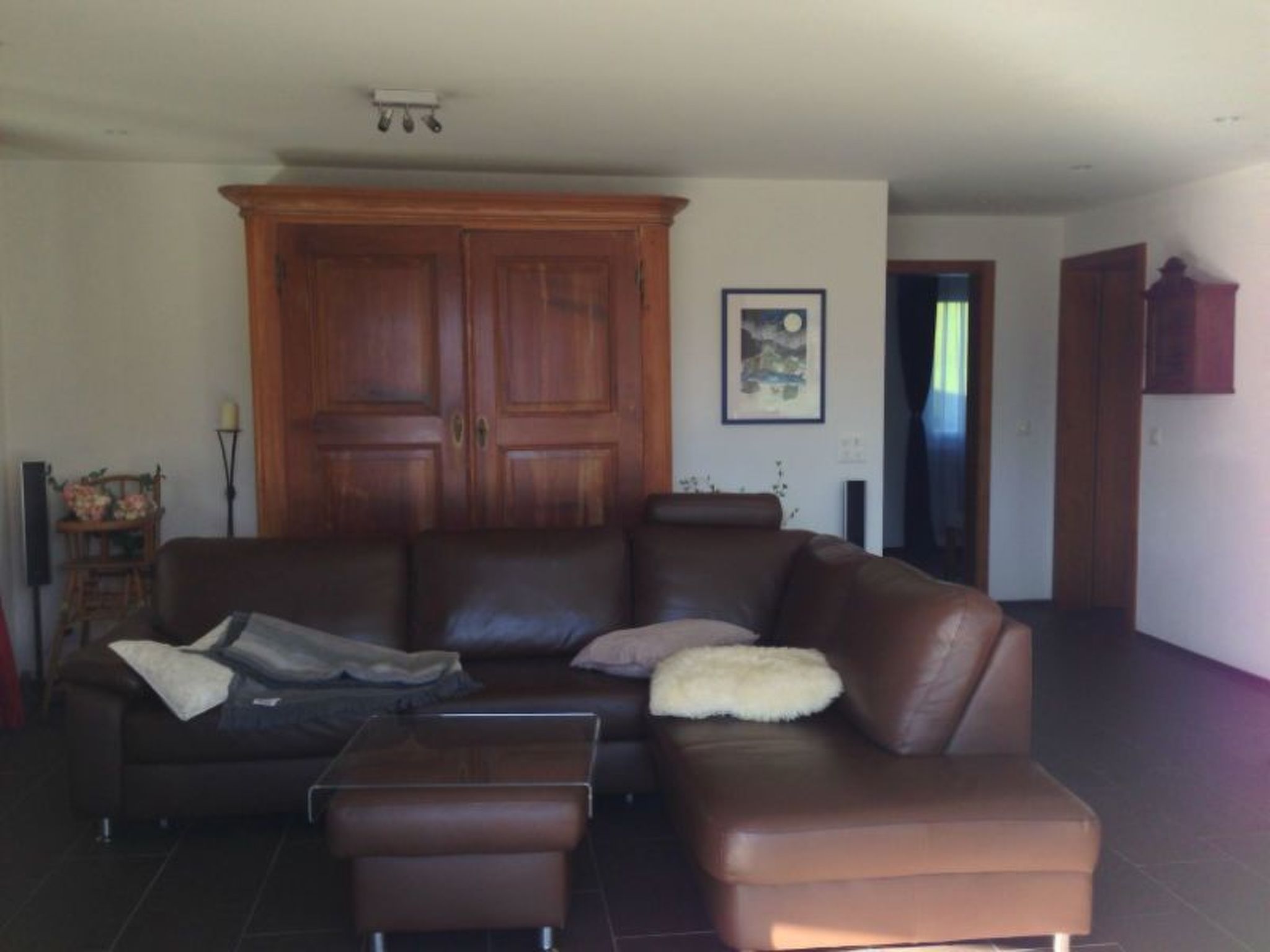 A living room with a brown leather sofa, a coffee table, and a cabinet.