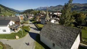 A rural village with traditional houses, a church, and a mountain backdrop.