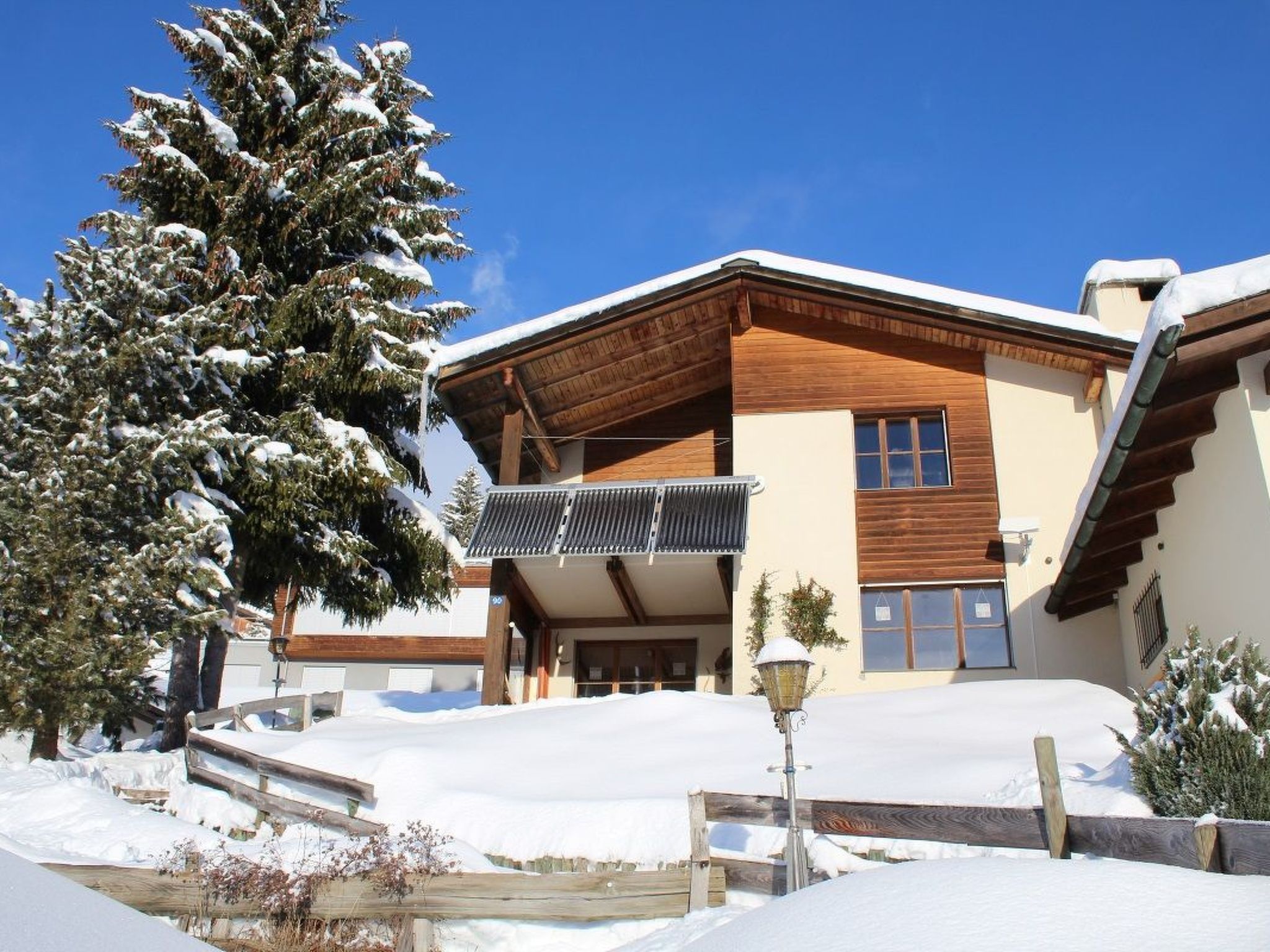 A modern building with a wooden facade, a balcony, and a snow-covered landscape.
