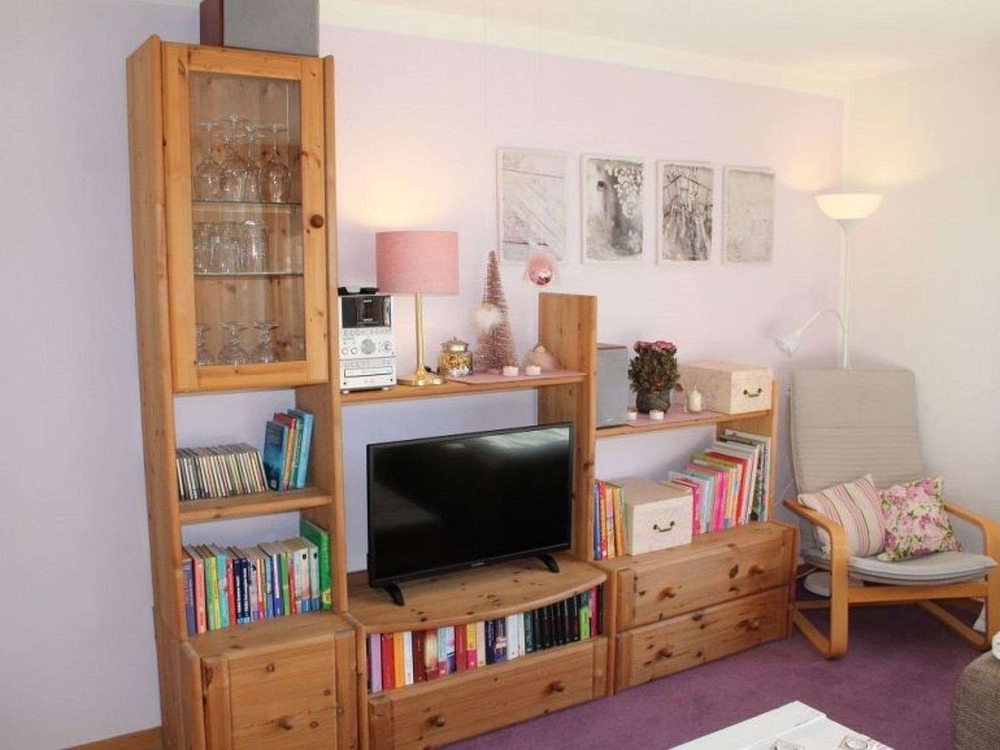 Ein Wohnzimmer mit Fernseher, Holzregalen, einem Sessel und Dekorationselementen.