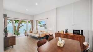A modern living room with a sofa, dining table, and kitchen area. - Room-charming Guest Room Retreat in Mare (Koh Samui)