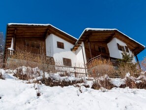 A two-story chalet with a wooden facade and white walls, situated on a snow-covered slope. - Ferienhaus Casa Lumina, Cumbel, (Cumbel), 42003B by Interhome (Cumbel)