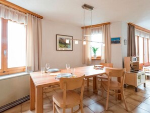 A dining area with a wooden table, chairs, and a hanging light fixture. - Ferienhaus Casa Lumina, Cumbel, (Cumbel), 42003B by Interhome (Cumbel)