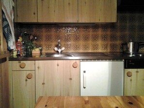 A kitchen with wooden cabinets, a stainless steel sink, and a dishwasher.
