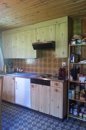 A kitchen with wooden cabinets, a stainless steel countertop, a built-in dishwasher, and a spice rack.