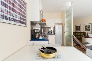 Eine kompakte Küche mit Mikrowelle, Herd und Kühlschrank. Ein Esstisch mit Tischdecke befindet sich im Vordergrund.