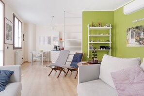Ein Wohnzimmer mit einer Couch, einem Esstisch und einem Bücherregal.