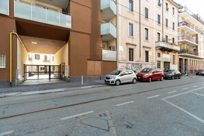 Ein Gebäude mit modernem Eingangsbereich, geparkten Autos und einer freien Straße.