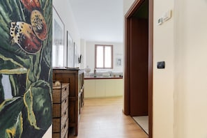 Ein Flur, der in eine Küche mit Holzboden, einem Fenster und einer Tür führt.